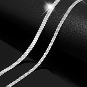 Macro shot of silver titanium steel snake chain necklace on black leather background