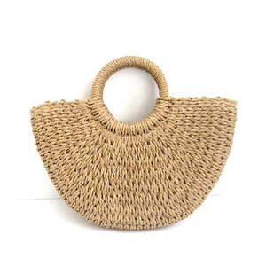 Detail showing the intricate hand-woven paper rope texture and round handle of this straw bag