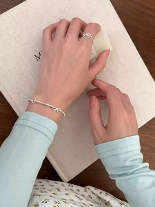 Dettaglio del set bracciale e anello in argento con fiocco indossato sul polso