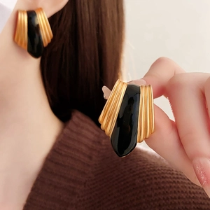 Detailed view of vintage gold and black enamel fan-shaped earrings worn by a model