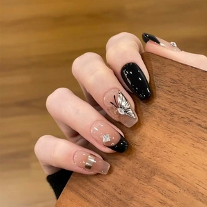 Gros plan d'ongles trapèze nude et noirs avec papillon argenté et diamant carré brillant