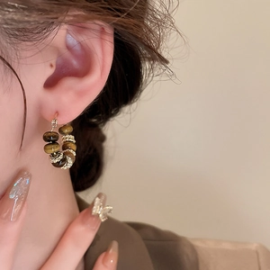 Close-up of vintage C-shape tiger eye earrings with gold metal accents on model