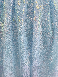 Macro detail of high-density light blue sequins on breathable mesh for cocktail dress