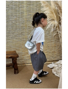 Silver mini crossbody bag for kids shown on a model in a rustic studio setting