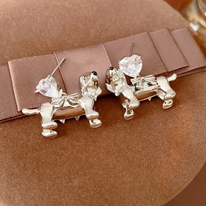 Macro detail of silver dachshund earrings with heart zirconia and small pearl accents