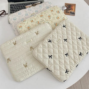 Detailed close-up of quilted laptop sleeves with cute rabbit and bow embroidery patterns