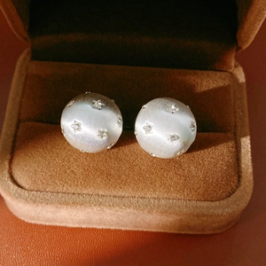 Gros plan de boucles d'oreilles demi-boule en argent brossé avec étoiles et diamants