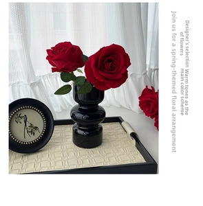 Detailed view of red velvet artificial roses in a modern black ceramic glazed vase