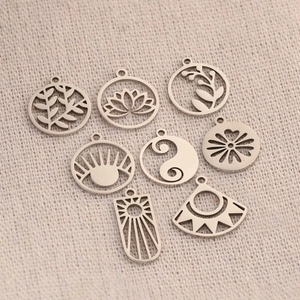 Polished silver stainless steel lotus and leaf pendants on beige linen background