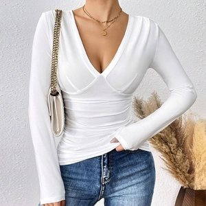 Detalle de un top blanco de manga larga con cuello en V mostrando el diseño cruzado de punto