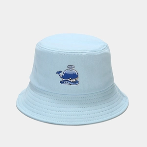Dettaglio di un cappello a secchiello azzurro con ricamo a forma di balena in cotone