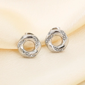 Macro shot of silver twisted hoop earrings with micro-pave zircons on silk fabric