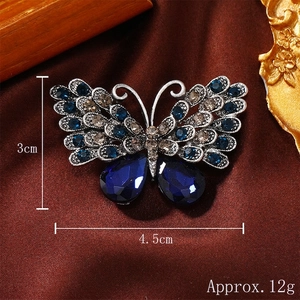 Retro butterfly brooch with blue rhinestones and silver alloy finish on brown silk background