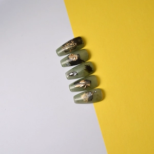 Detail of ballerina press-on nails with jade texture, ink patterns and gold leaf accents
