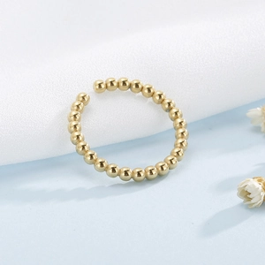 Gros plan d'une bague ouverte à billes dorées minimaliste au fini métallique