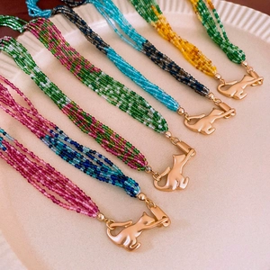 Detailed view of multilayer beaded necklaces with golden cat pendants on a ceramic plate