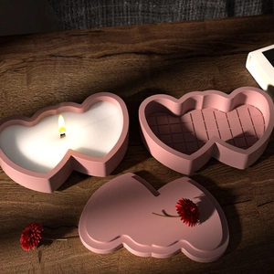 Dual heart-shaped pink silicone candle molds with matte finish on a dark wood background