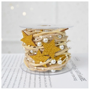 Detail of Christmas ribbon with golden stars, white pearls, and rustic jute twine on reel