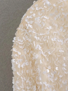 Macro view of cream fabric with dense white sequins on a stylish women's jacket