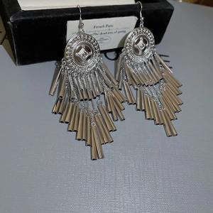 Detail of silver round engraved base with long metal tassels on vintage bohemian earrings
