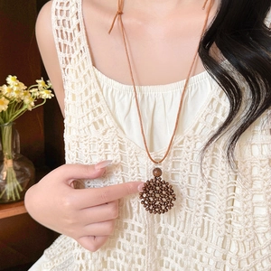 Long Bohemian heart woven necklace with brown wood beads on white lace summer dress