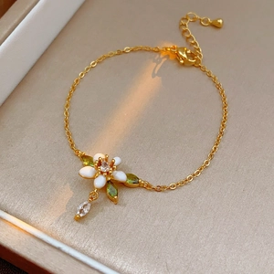 Dettaglio di un bracciale floreale dorato con pietre bianche e verdi in portagioie