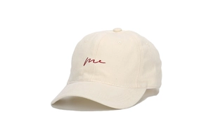 Macro shot of red script embroidery me on cream white cotton baseball cap fabric