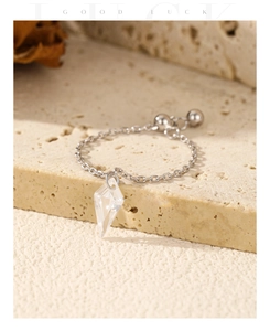 Macro shot of silver chain ring with a clear geometric diamond-shaped crystal pendant