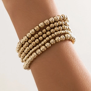Detailed view of multilayered gold beaded bracelet set with heart charm on wrist