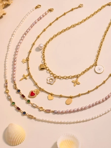 Details mehrlagiger Goldketten mit bunten Zirkonherzen und eleganten Perlenakzenten