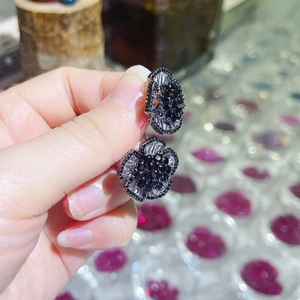 Macro shot of camellia stud earrings with black and clear zircons held in hand