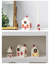 Detail view of festive ceramic Christmas house ornaments and candle holders on white shelves