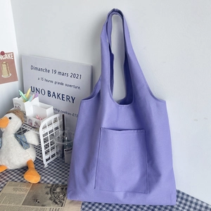 Detail of purple canvas tote bag with outer pocket in a cozy lifestyle setting