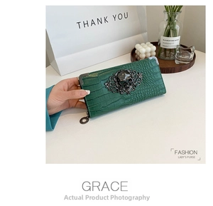 Detail of dark green crocodile pattern wallet with vintage metal skull and baroque pattern