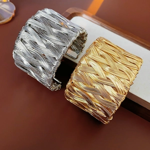Close-up of vintage twisted weave cuff bracelet in gold and silver finishes on a tray