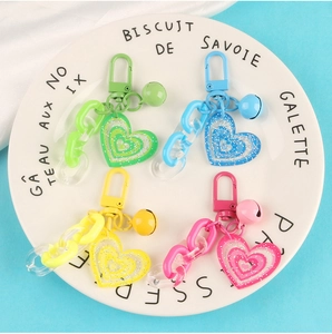 Colorful acrylic heart keychains with glitter charms and bells in four vibrant pastel colors