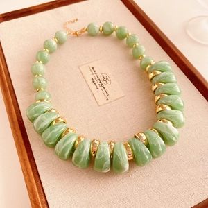 Détail macro d'un collier vintage avec perles en résine marbrée vert clair et métal doré