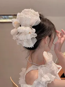 Détail de la pince à cheveux en dentelle beige et organza en forme de nœud floral