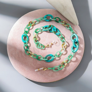 Detail of green acrylic glasses chain with marble texture links and gold metal clasps