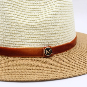 Detail of two-tone straw hat with orange velvet ribbon and golden M metal buckle
