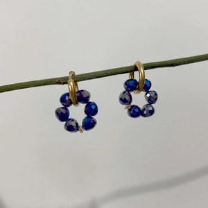 Detailed shot of 18K gold stainless steel hoop earrings with deep blue faceted beads