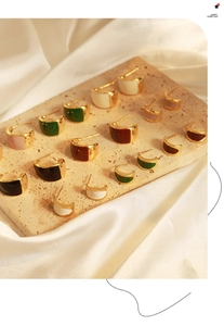 Detailed display of colorful enamel C-shaped crescent earrings on a textured stone plate