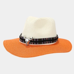 Detail of bull head buckle on retro straw cowboy hat with bright orange brim