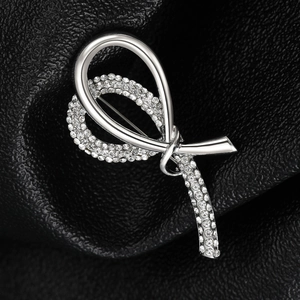 Macro shot of silver bow brooch with sparkling crystals on black leather background