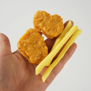 Realistic fried chicken nugget and French fries food models held in hand for scale