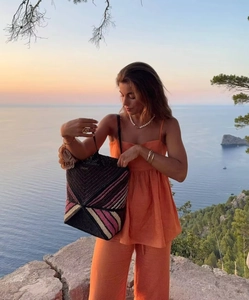 Détail d'un sac à main tissé noir aux rayures roses et jaunes lors d'un coucher de soleil