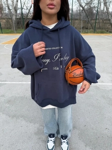 Λεπτομέρεια από μπλε oversized hoodie με τύπωμα και τσάντα σε σχήμα μπάλας μπάσκετ