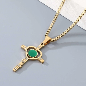 Close-up of gold cross necklace with emerald center stone and small white diamonds