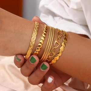 Detailed layered set of 18K gold plated minimalist cuff and chain bracelets on wrist