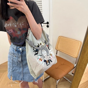 Detail of canvas tote bag with horse embroidery and woven rope shoulder strap